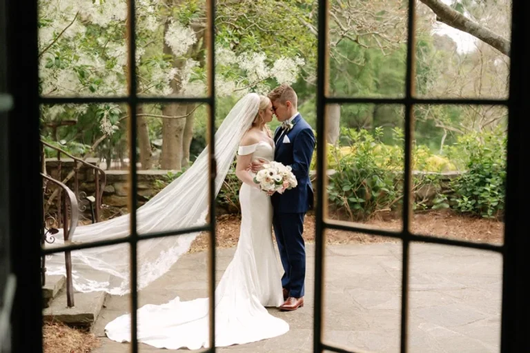 View of a bride and groom embracing through a window